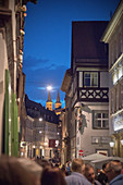 Menschen stehen in den Gassen der Altstadt Bamberg vor dem berühmten Gasthof Zum Schlenkerla, im Hintergrund sind die Kirchtürme von St. Michael zu sehen, Region Franken, Bayern, Deutschland, UNESCO Welterbe