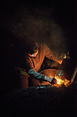 old charcoal burner woman lights kiln at night, charcoal production, Aalen, Baden-Wuerttemberg, Germany