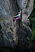 Young woman climbing at a rock face, Pottenstein, Franconia, Germany