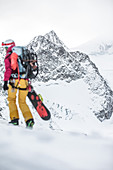 Young female snowboarder walking through the deep powder snow apart slopes, Pitztal, Tyrol, Austria