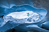 Junger Snowboarder springt eine Gletscherhöle herunter, Pitztal, Tirol, Österreich