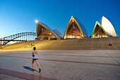 jogger and Sydney Opera House at dusk, with Harbour Bridge in the background.