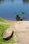 grüner Sonnenschirm im kleinem Boot, Rentner Paar landet Holzboot, Sonntagsausflug, komisch, Candes-Saint-Martin, Loire Region, Frankreich