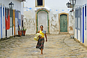 'Local brazilian woman walking through the historic center; Paraty, Espirito Santo, Brazil. The beautiful colonial town of Paraty has been a UNESCO World Heritage Site since 1958.'