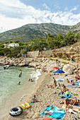 Tourists on a beach near Paklina campsite in Ivan Dolac village, Hvar island, Croatia.
