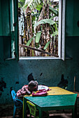 Little local girl resting her head on a table in a poor area, Sao Tome, Sao Tome and Principe, Africa