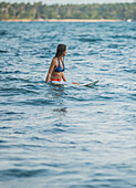 Young female surfer waiting for a wave in the water, Sao Tome, Sao Tome and Principe, Africa