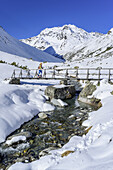 Frau auf Skitour steigt über Brücke Richtung Westfalenhaus auf, Hoher Seeblaskogel im Hintergrund, Hoher Seeblaskogel, Sellrain, Stubaier Alpen, Tirol, Österreich