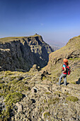 Woman hiking standing at Mashai Pass, Rhino Peak in background, Mashai Pass, Garden Castle, Mzimkhulu Wilderness Area, Drakensberg, uKhahlamba-Drakensberg Park, UNESCO World Heritage Site Maloti-Drakensberg-Park, KwaZulu-Natal, South Africa