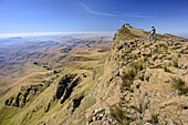 Frau beim Wandern steht über Felswand des Giant's Castle, Tiefblick auf Little Berg, vom Giant's Castle, Drakensberge, uKhahlamba-Drakensberg Park, UNESCO Welterbe Maloti-Drakensberg-Park, KwaZulu-Natal, Südafrika