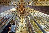 Couple admiring the ceiling of the Sagrada Familia Temple by Antoni Gaudi. Barcelona, Spain.