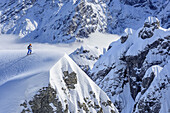 Person auf Skitour steigt auf Schneekuppe vor Felswand auf, Hochalm, Hochkalter, Nationalpark Berchtesgaden, Berchtesgadener Alpen, Berchtesgaden, Oberbayern, Bayern, Deutschland