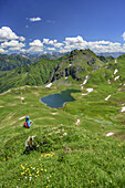 Frau sitzt in Wiese und blickt auf Tilisunasee und Tilisuna-Seehorn, Rätikon-Höhenweg, Rätikon, Vorarlberg, Österreich