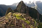 View of the Machu Picchu landscape. Machu Picchu is a city located high in the Andes Mountains in modern Peru. It lies 43 miles northwest of Cuzco at the top of a ridge, hiding it from the Urabamba gorge below. The ridge is between a block of highland and