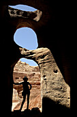 Silhouette of a woman at the entrance of a cave near the theatre. Jordan (Hashemite Kingdom of), Ma´an Governorate (Maan), ancient city of Petra. Model Released.
