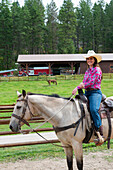 Cowgirl (Wrangler) on horse at Averill´s Flathead Lake Lodge, a dude ranch near Kalispell, Montana, United States.