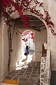 Woman walking through an archway in town center Chora, Ios, Cyclades Islands, Greek Islands, Greece, Europe.