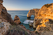 Sunrise on the cliffs and turquoise water of the ocean, Praia da Marinha, Caramujeira, Lagoa Municipality, Algarve, Portugal, Europe