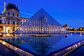 The Louvre Pyramid and Palace reflected in a still pool within the Napoleon Courtyard at twilight, Paris, France, Europe