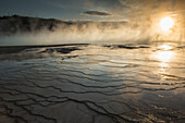 'Evening light shines through the steam rising over the Grand Prismatic Spring in Yellowstone National Park; Wyoming, United States of America'