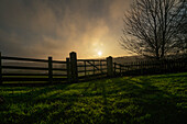 'Sunlight shining through the clouds and a shadow of a fence cast on the grass; Beamish, England'