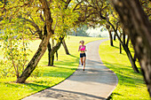 Attractive young woman jogging on Park Trail in the Early Morning.  Healthy Lifestyle Fitness Running Concept