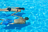 'A couple swimming underwater in a pool, Saint Georges Caye Resort; Belize City, Belize'