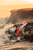 'Sea water and molten rock splatter together as a wave crashes onto the Pahoehoe lava flowing from Kilauea into the Pacific Ocean near Kalapana; Island of Hawaii, Hawaii, United States of America'