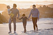 Happy young family walking on the beach at sunset