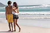 Rear view of a young couple walking on beach