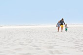 Man with his children walking on the beach