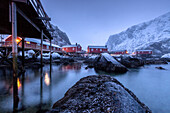 Typical fishermen houses called rorbu in the snowy landscape at dusk Nusfjord Nordland County Lofoten Islands Norway Europe