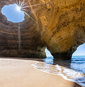 The sun shines through the natural rocky windows inside the caves of Benagil Faro District Algarve Portugal Europe