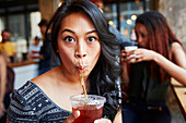 Woman drinking cold drink with straw in cafe