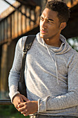 Mixed Race man with shirt draped over shoulders listening to headphones