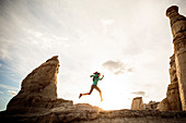 Woman running in canyon wearing backpack