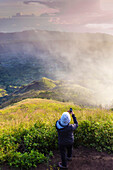 Man hiker taking photo with mobilephone on the top of Batur volcano,Bali,Indonesia