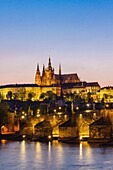 Prague Castle St Vitus Cathedral Charles bridge and Vtlava River illuminated at dusk Czech Republic.