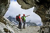Blick aus Felsstollen auf Mann und Frau am Klettersteig Sentiero dei Fiori, Sentiero dei Fiori, Adamello-Presanella-Gruppe, Trentino, Italien