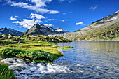 River flowing into mountain lake with Lobbia Alta in background, hut rifugio Madron, Adamello-Presanella Group, Trentino, Italy