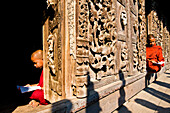 Myanmar (Burma), Mandalay Division, Mandalay, Shwe Nan Daw temple, novice A Shin Tay Zaw Barta (14 years old) reading in front of the carved panels made of teak