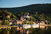 View from Mainbruecke bridge to city and excursion boats on Main river with reflection, Miltenberg, Spessart-Mainland, Bavaria, Germany