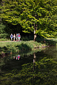 Group of young women hike along trail along Aubachseen lakes , Habichsthal, Spessart-Mainland, Bavaria, Germany