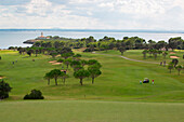 Golfer auf Fairway von Bahn 12 von Golfplatz Club de Golf Alcanada mit Leuchtturm Faro de Alcanada im Hintergrund, nahe Port d'Alcudia, Mallorca, Balearen, Spanien