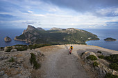 Radfahrer auf Schotterweg am Berg mit Blick auf die Halbinsel Cap de Formentor, nahe Cap de Formentor, Mallorca, Balearen, Spanien