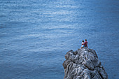 Couple sit on rocks at Cala de Sa Calobra bay and look to the sea, Sa Calobra, Mallorca, Balearic Islands, Spain