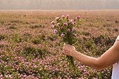 Caucasian woman holding bouquet of flowers in field