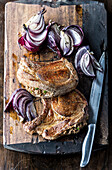 Pork chops and onions on cutting board with knife
