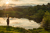 A woman looks out over Loughrigg Tarn near Ambleside in The Lake District National Park, Cumbria, England, United Kingdom, Europe
