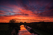 Barges lay still on the Shropshire Union canal as the dawn light sweeps across the sky above Beeston Castle, Cheshire, England, United Kingdom, Europe